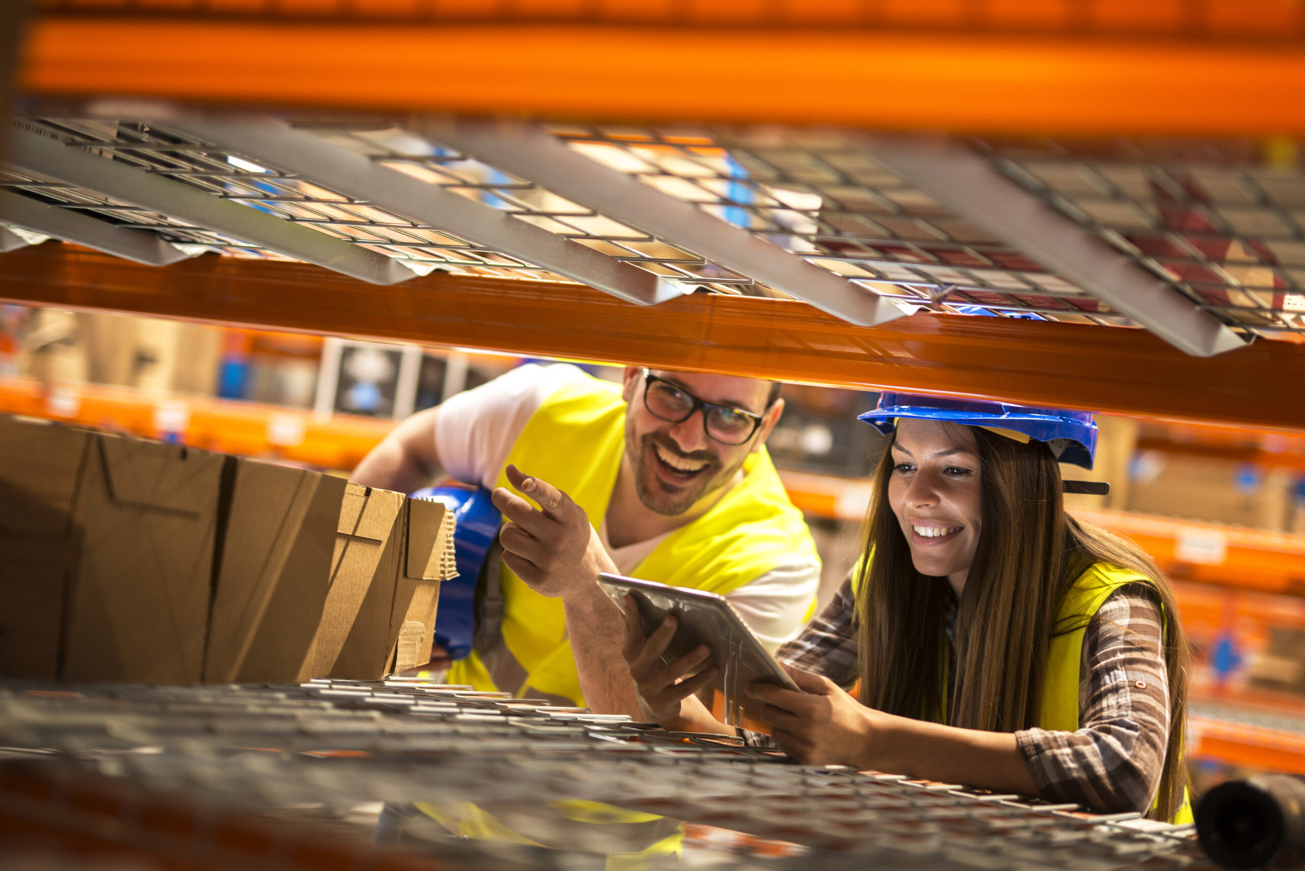 Warehouse workers counting boxes on shelves in large distribution warehouse.